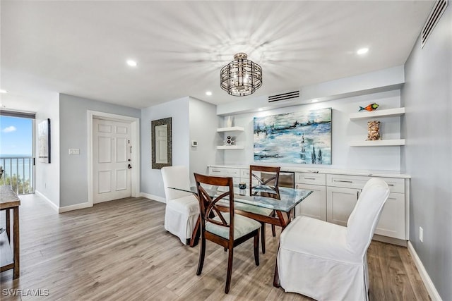 dining space with light hardwood / wood-style floors and a chandelier