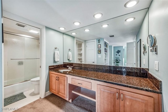 full bathroom with enclosed tub / shower combo, vanity, and toilet