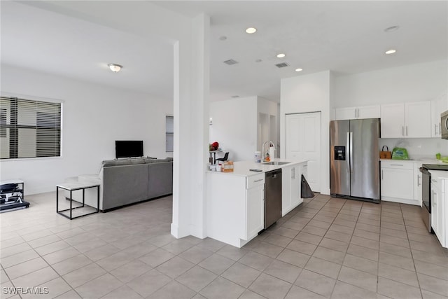 kitchen featuring light tile patterned floors, kitchen peninsula, sink, appliances with stainless steel finishes, and white cabinets