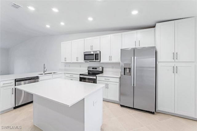 kitchen with appliances with stainless steel finishes, lofted ceiling, light tile patterned flooring, and white cabinets