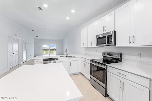 kitchen featuring kitchen peninsula, sink, appliances with stainless steel finishes, lofted ceiling, and light tile patterned flooring