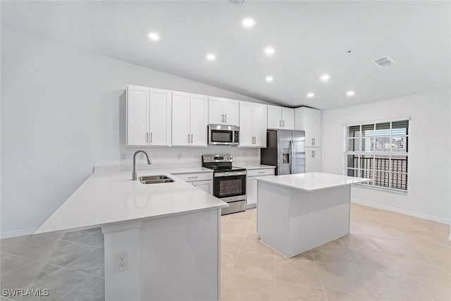 kitchen featuring a center island, vaulted ceiling, stainless steel appliances, white cabinetry, and sink