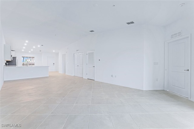 unfurnished living room featuring lofted ceiling and light tile patterned flooring