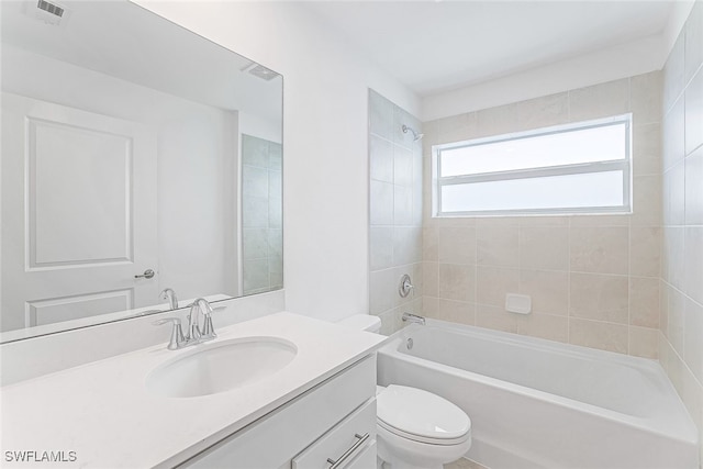 full bathroom featuring tiled shower / bath, vanity, and toilet