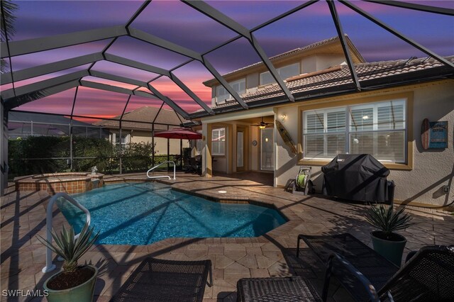 pool at dusk with ceiling fan, a grill, an in ground hot tub, a patio area, and glass enclosure