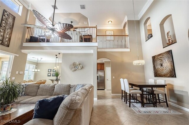 living room featuring ornamental molding, light tile patterned flooring, a towering ceiling, and ceiling fan