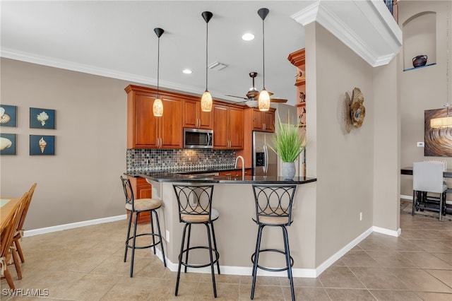 kitchen with appliances with stainless steel finishes, crown molding, and decorative light fixtures