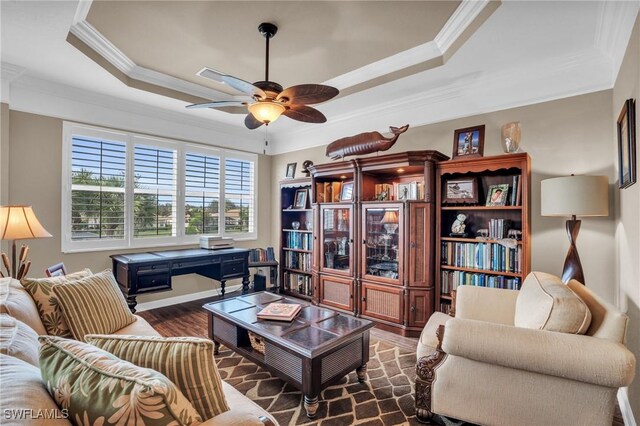 living room featuring a tray ceiling, ceiling fan, dark hardwood / wood-style floors, and crown molding