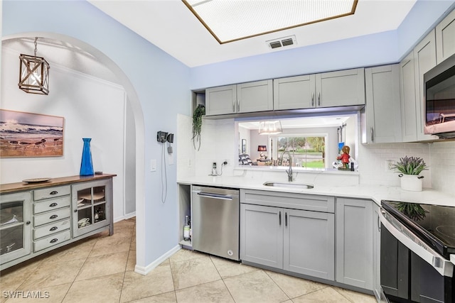 kitchen featuring gray cabinets, appliances with stainless steel finishes, backsplash, and sink