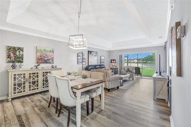 dining room with an inviting chandelier, wood-type flooring, and a tray ceiling