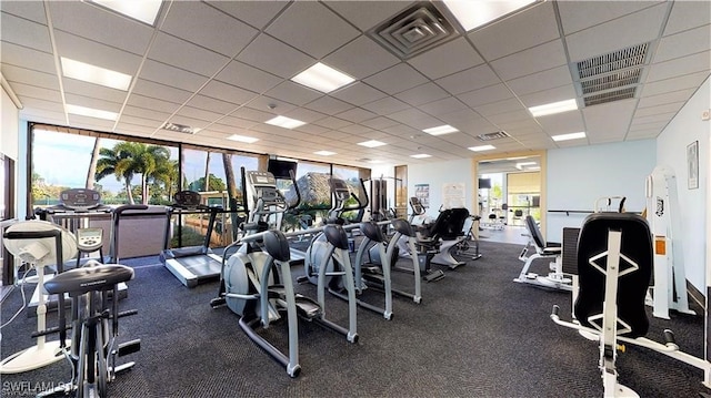 exercise room with floor to ceiling windows, a paneled ceiling, and a wealth of natural light