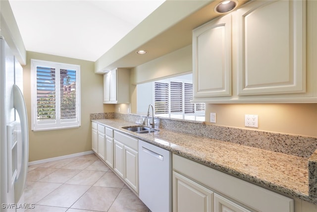 kitchen featuring sink, white cabinetry, light stone countertops, light tile patterned flooring, and white appliances