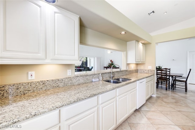 kitchen featuring vaulted ceiling, white dishwasher, sink, white cabinets, and light stone counters