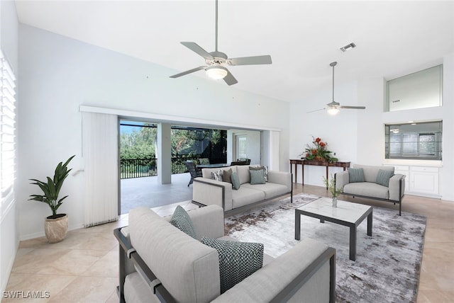 living area featuring light tile patterned floors, ceiling fan, a high ceiling, and visible vents