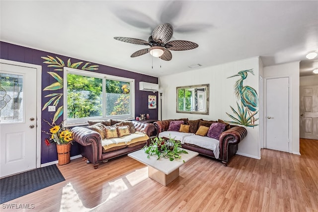 living room with a wall mounted AC, a wealth of natural light, ceiling fan, and light hardwood / wood-style floors