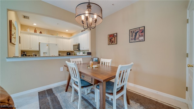 tiled dining room with a chandelier