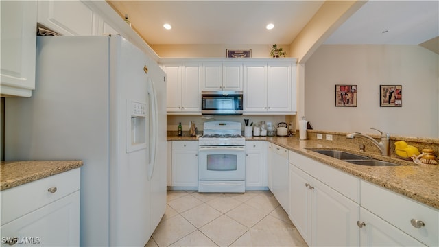 kitchen featuring white appliances, light stone countertops, white cabinetry, a sink, and light tile patterned flooring