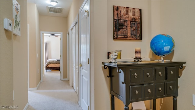 hall with visible vents, light carpet, and baseboards