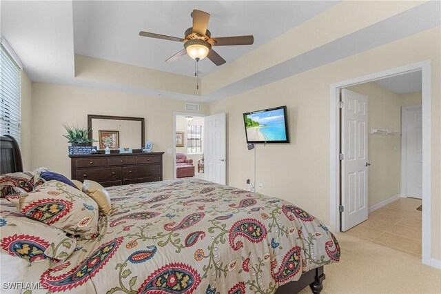 bedroom with light colored carpet, ceiling fan, and a raised ceiling