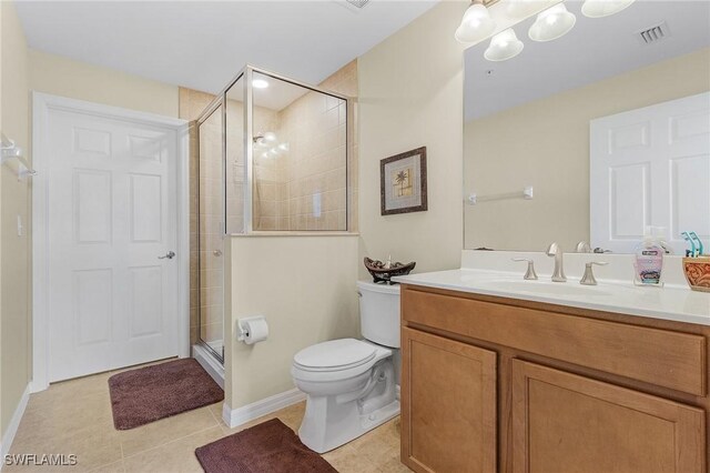 bathroom featuring tile patterned floors, toilet, a shower with door, and vanity