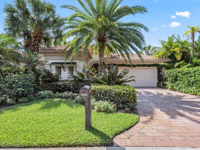 mediterranean / spanish-style home featuring a garage and a front yard