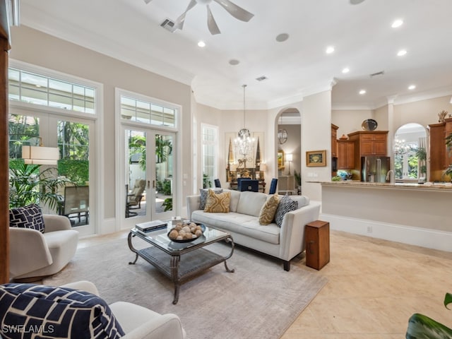 living room featuring ceiling fan with notable chandelier, plenty of natural light, ornamental molding, and french doors