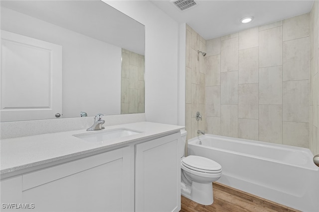 full bathroom featuring hardwood / wood-style flooring, vanity, toilet, and tiled shower / bath combo