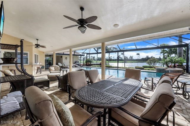 view of patio / terrace with a swimming pool with hot tub, ceiling fan, glass enclosure, and a water view