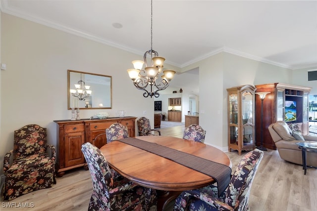 dining room with an inviting chandelier, crown molding, and light hardwood / wood-style floors