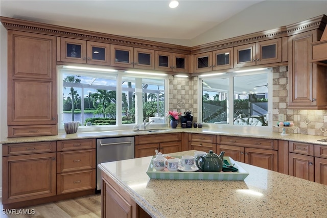 kitchen featuring sink, dishwasher, light stone counters, tasteful backsplash, and vaulted ceiling