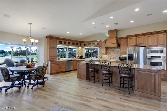 kitchen with premium range hood, appliances with stainless steel finishes, backsplash, a kitchen island, and vaulted ceiling