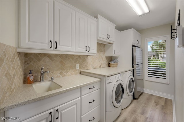 laundry area with cabinets, washing machine and clothes dryer, sink, and light wood-type flooring