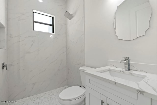 bathroom with toilet, a tile shower, and vanity