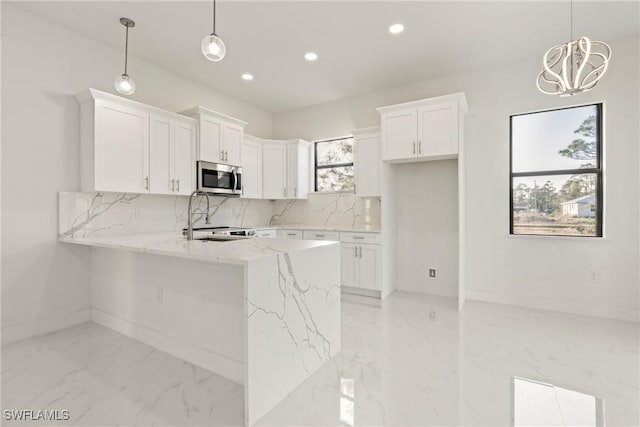 kitchen featuring pendant lighting, decorative backsplash, sink, white cabinets, and light stone counters