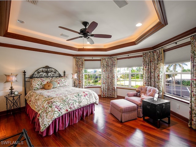 bedroom with a raised ceiling, multiple windows, ceiling fan, and dark hardwood / wood-style flooring