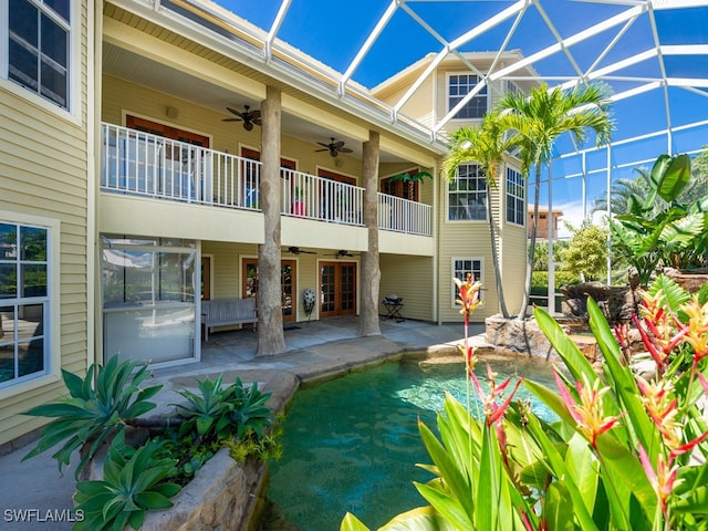 view of pool featuring glass enclosure, ceiling fan, and a patio