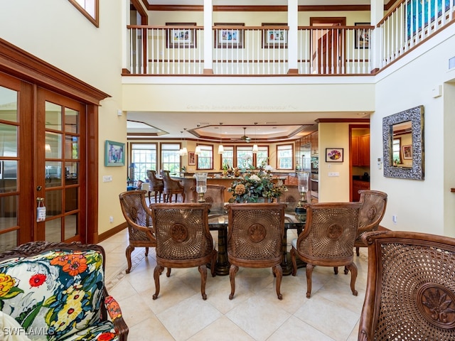 tiled dining space featuring a towering ceiling and ornamental molding