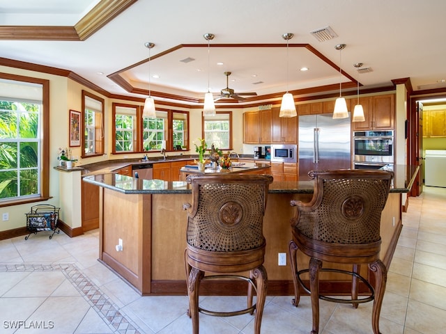 kitchen featuring kitchen peninsula, built in appliances, decorative light fixtures, and a wealth of natural light