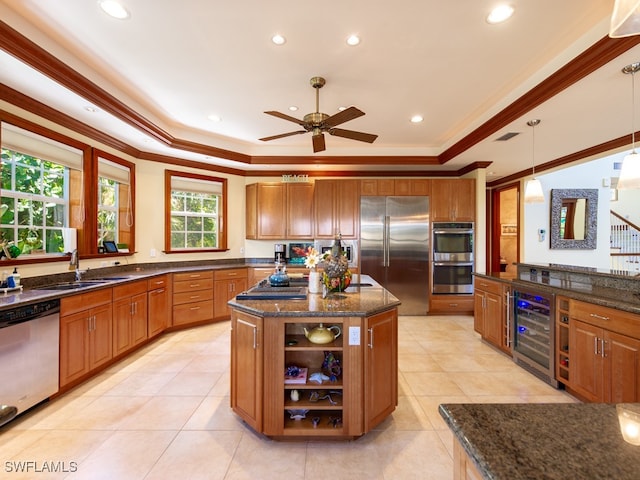 kitchen with a center island, sink, stainless steel appliances, beverage cooler, and decorative light fixtures