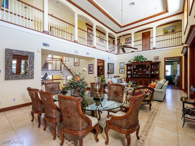 dining room featuring ceiling fan, crown molding, light tile patterned floors, and a high ceiling