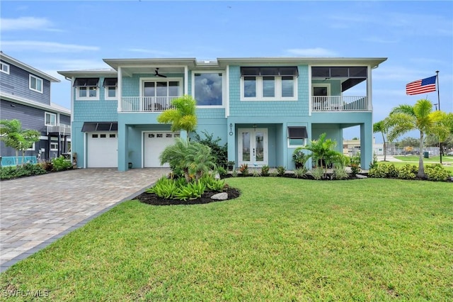 view of front of house featuring ceiling fan, a garage, french doors, and a front lawn