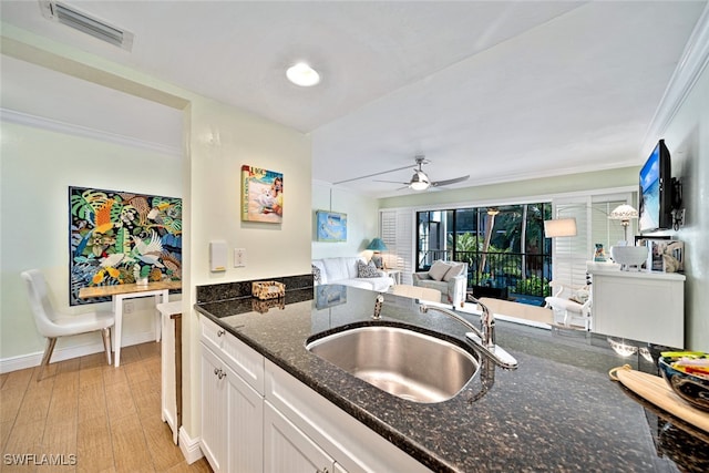 kitchen with dark stone counters, light hardwood / wood-style flooring, sink, ceiling fan, and white cabinets