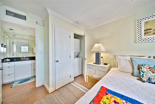 bedroom featuring crown molding, sink, stacked washer / dryer, and light hardwood / wood-style floors