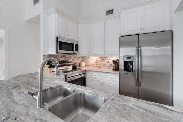 kitchen with white cabinetry, light stone counters, and stainless steel appliances