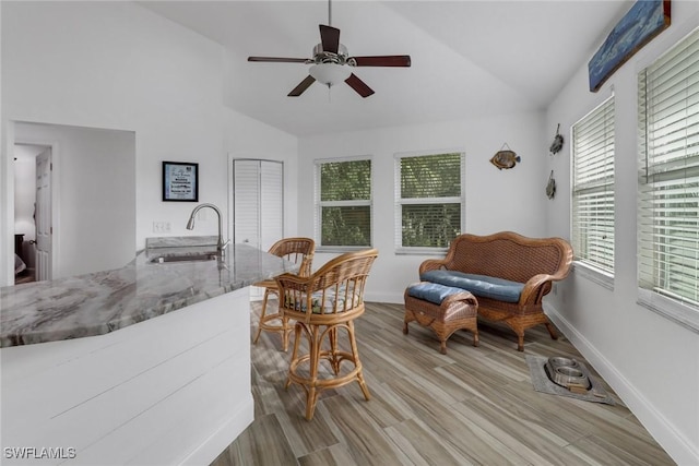 living area featuring lofted ceiling, sink, light hardwood / wood-style flooring, and ceiling fan