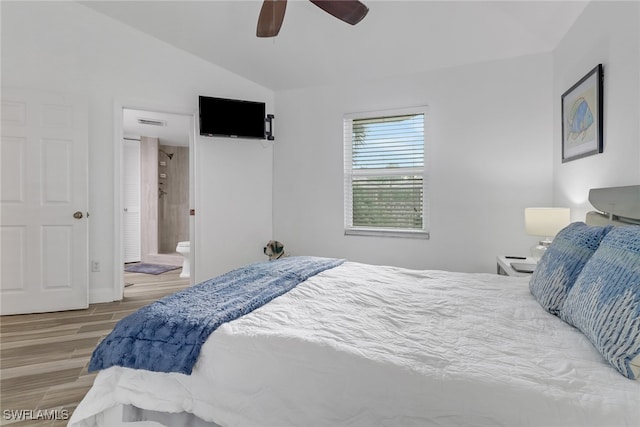 bedroom with ceiling fan, ensuite bath, lofted ceiling, and hardwood / wood-style flooring