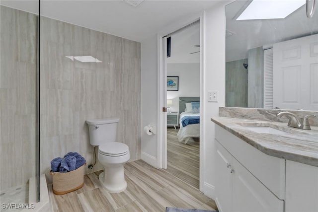 bathroom featuring vanity, hardwood / wood-style floors, a skylight, and toilet