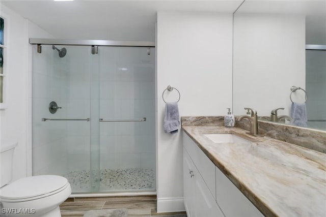 bathroom featuring vanity, a shower with door, and toilet