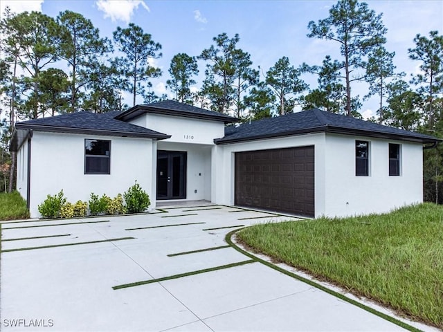 prairie-style house featuring stucco siding, concrete driveway, an attached garage, and french doors