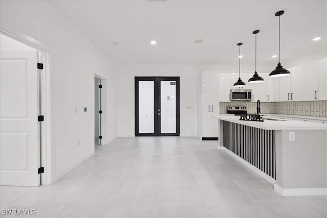 kitchen with hanging light fixtures, french doors, appliances with stainless steel finishes, white cabinetry, and decorative backsplash